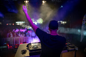 DJ LUKE D steht an seinem Player und feiert mit der Menschenmenge